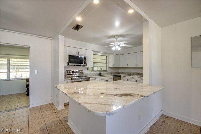 kitchen featuring white cabinetry, sink, kitchen peninsula, stainless steel appliances, and light stone countertops