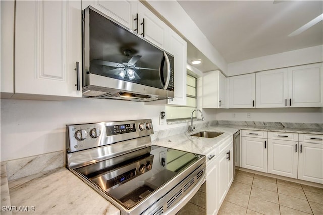 kitchen with sink, white cabinetry, stainless steel appliances, light stone countertops, and light tile patterned flooring