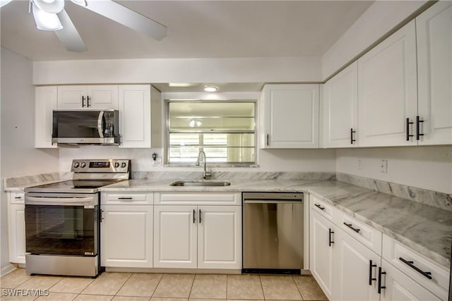 kitchen featuring light tile patterned flooring, white cabinetry, sink, ceiling fan, and stainless steel appliances