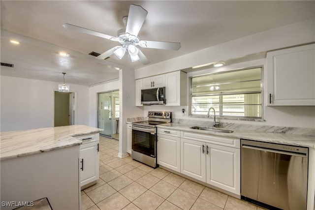 kitchen featuring appliances with stainless steel finishes, white cabinetry, sink, hanging light fixtures, and light stone counters