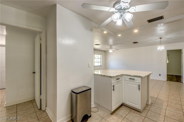 kitchen featuring light tile patterned flooring, pendant lighting, white cabinetry, ceiling fan, and light stone counters