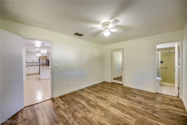 unfurnished bedroom with stainless steel refrigerator, ceiling fan, connected bathroom, and light hardwood / wood-style floors