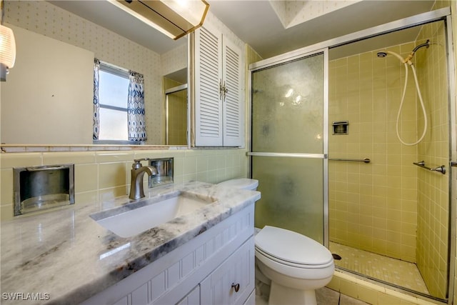 bathroom with tile walls, decorative backsplash, vanity, an enclosed shower, and toilet