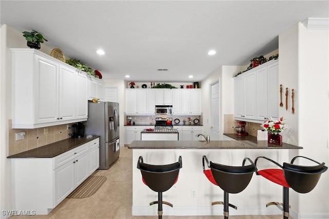 kitchen with sink, appliances with stainless steel finishes, a kitchen breakfast bar, kitchen peninsula, and white cabinets