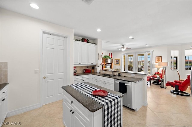 kitchen featuring sink, a center island, dishwasher, kitchen peninsula, and white cabinets