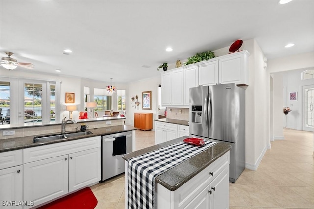 kitchen featuring sink, light tile patterned floors, backsplash, stainless steel appliances, and white cabinets