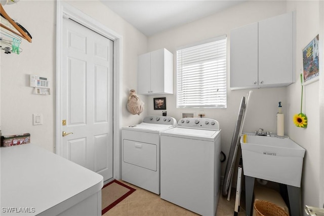 laundry area with cabinets, washer and clothes dryer, sink, and light tile patterned floors