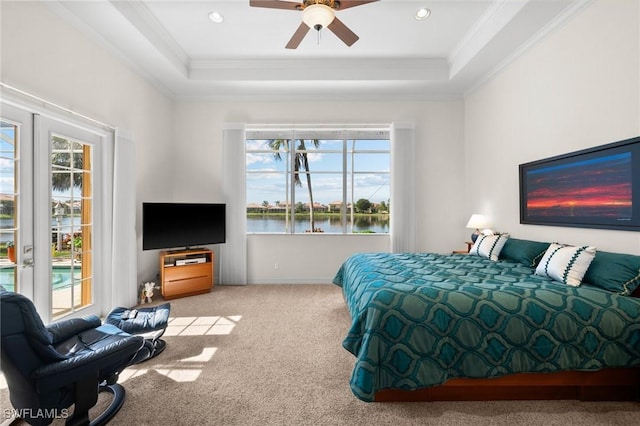 carpeted bedroom featuring ornamental molding, access to exterior, ceiling fan, a tray ceiling, and french doors