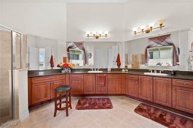 bathroom featuring a shower with door, vanity, a high ceiling, and tile patterned floors