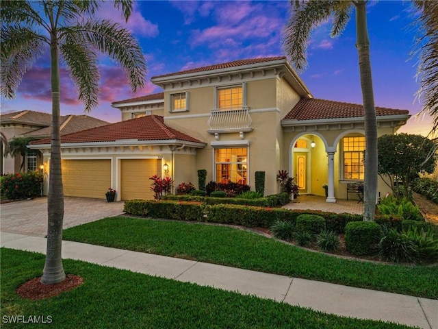 mediterranean / spanish home featuring a garage and a lawn