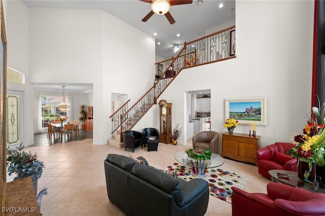 living room featuring a towering ceiling, light tile patterned floors, and ceiling fan