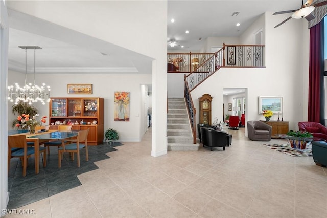 interior space with crown molding, light tile patterned flooring, ceiling fan with notable chandelier, and a high ceiling