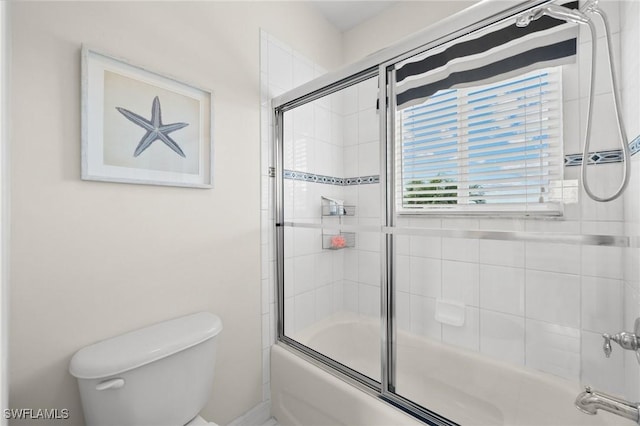 bathroom featuring toilet and bath / shower combo with glass door