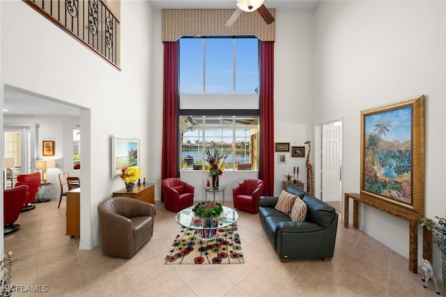 living room with a towering ceiling, light tile patterned floors, and ceiling fan