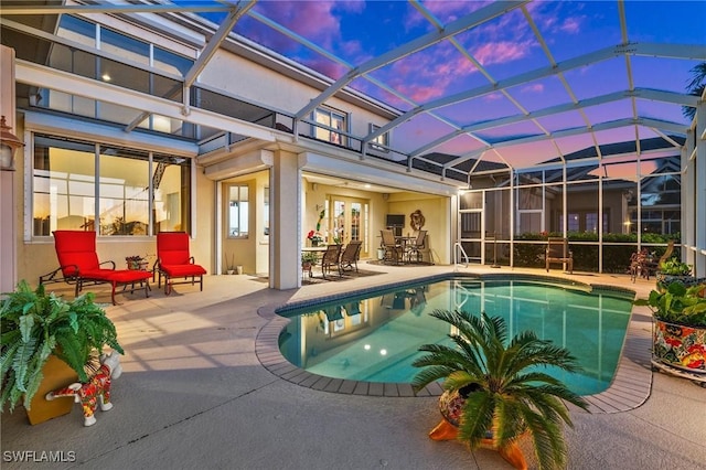 pool at dusk with a lanai and a patio