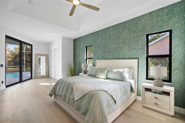 bedroom featuring multiple windows, access to outside, and light hardwood / wood-style floors