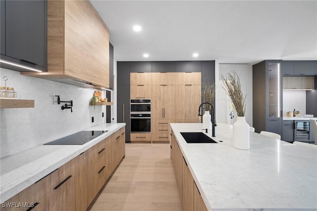 kitchen with a kitchen island, sink, decorative backsplash, light hardwood / wood-style floors, and black appliances