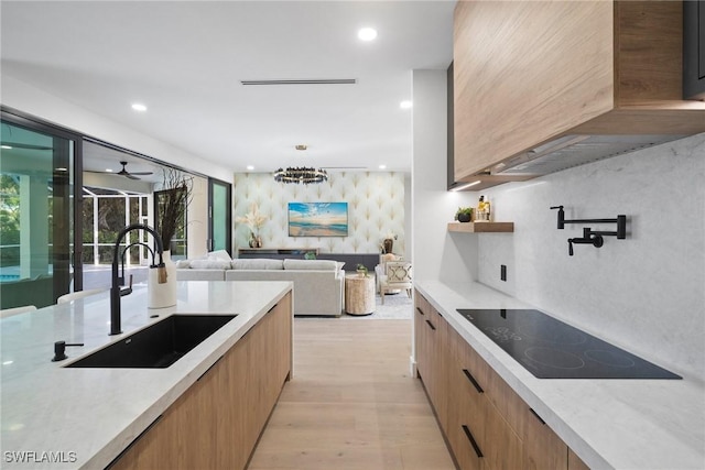 kitchen with sink, light hardwood / wood-style flooring, light stone countertops, and ceiling fan