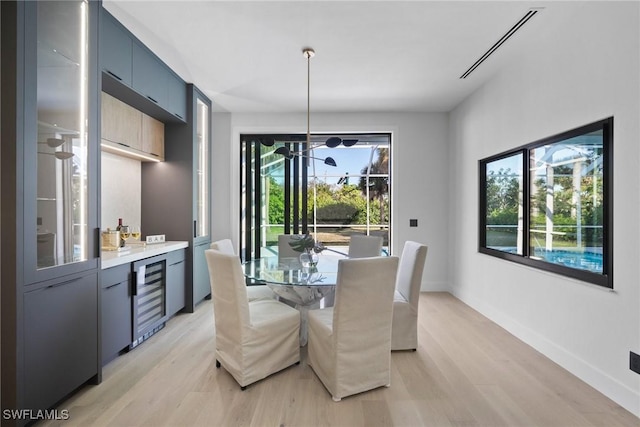 dining space with beverage cooler and light wood-type flooring