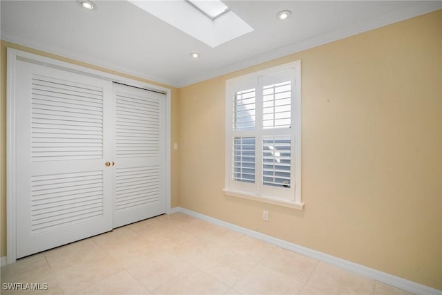 unfurnished bedroom featuring a closet, crown molding, and a skylight