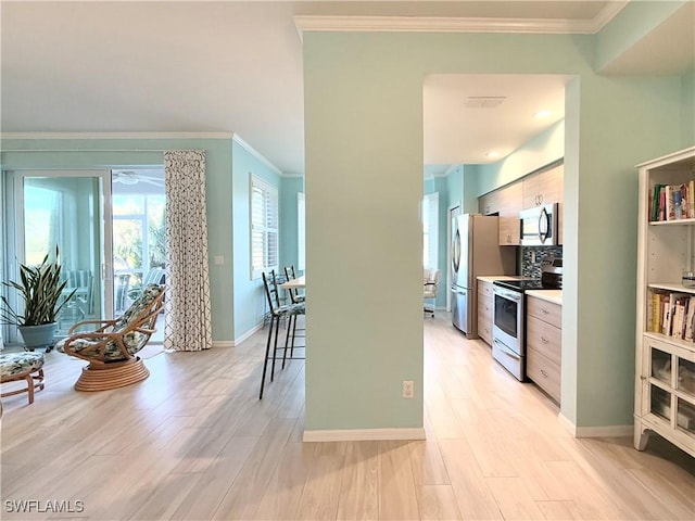 kitchen with stainless steel appliances, ornamental molding, light wood-type flooring, and decorative backsplash