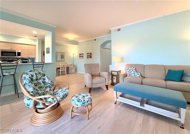 living room with ornamental molding and light hardwood / wood-style floors