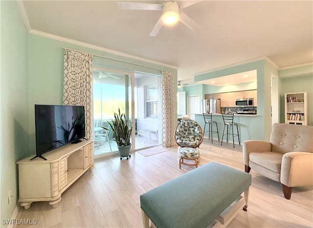 living room featuring ornamental molding, light hardwood / wood-style floors, and ceiling fan