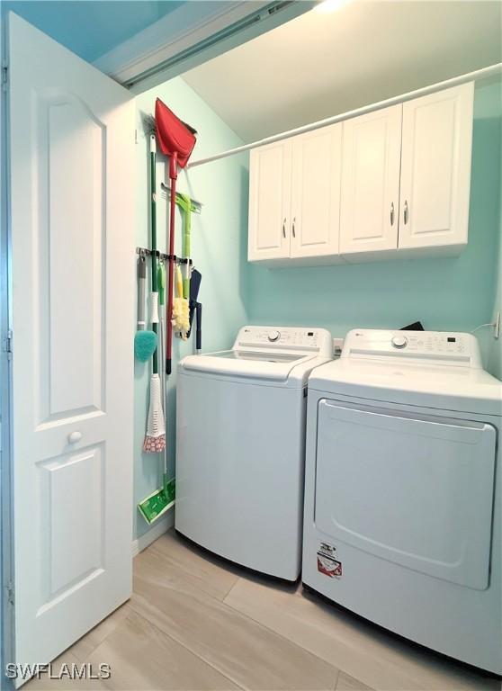 laundry area featuring cabinets, separate washer and dryer, and light hardwood / wood-style floors