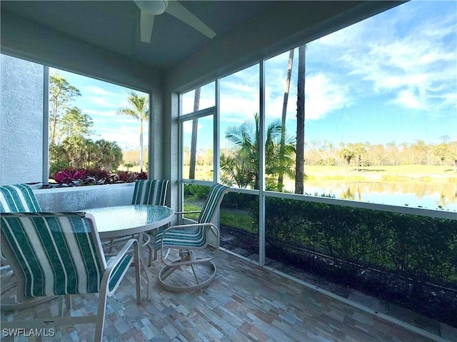 sunroom featuring ceiling fan and a water view