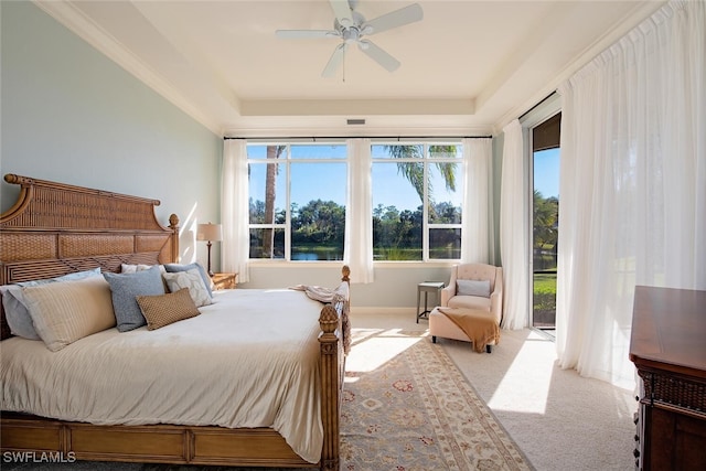 carpeted bedroom featuring a water view, access to exterior, ceiling fan, and a tray ceiling