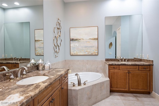 bathroom featuring a relaxing tiled tub, vanity, and tile patterned floors