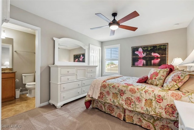 bedroom featuring light colored carpet, ceiling fan, and ensuite bathroom