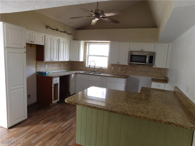 kitchen featuring lofted ceiling, sink, stone countertops, light hardwood / wood-style flooring, and white cabinets