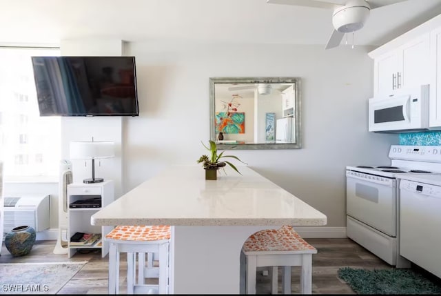 kitchen with white appliances, a kitchen breakfast bar, dark hardwood / wood-style flooring, and white cabinets