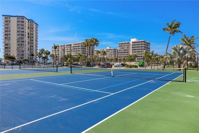 view of tennis court featuring fence and a city view