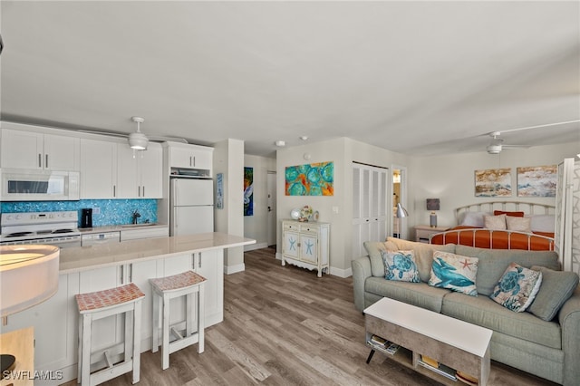 kitchen featuring open floor plan, white appliances, a ceiling fan, and a kitchen breakfast bar