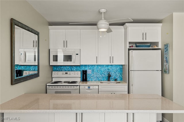 kitchen featuring light stone counters, tasteful backsplash, white cabinetry, a sink, and white appliances