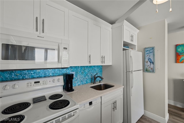 kitchen featuring tasteful backsplash, white cabinets, a sink, wood finished floors, and white appliances