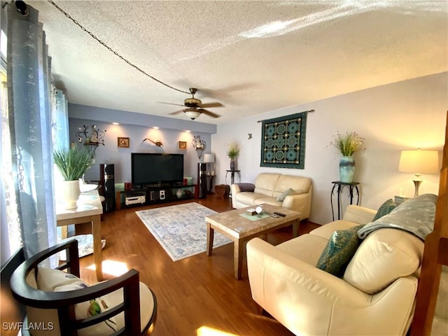 living room with ceiling fan, wood-type flooring, and a textured ceiling