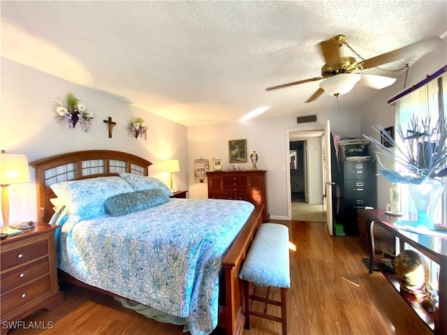 bedroom featuring ceiling fan, hardwood / wood-style floors, and a textured ceiling