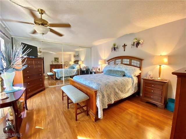 bedroom featuring ceiling fan, light hardwood / wood-style floors, and a textured ceiling