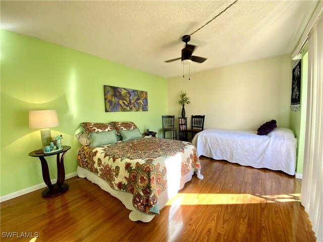 bedroom featuring ceiling fan, wood-type flooring, and a textured ceiling