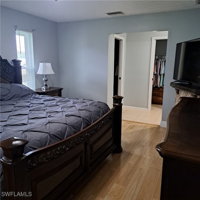 bedroom with a closet, visible vents, a spacious closet, and light wood-style floors