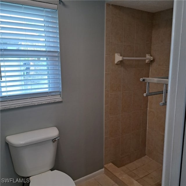 bathroom with toilet, tile patterned floors, and a tile shower