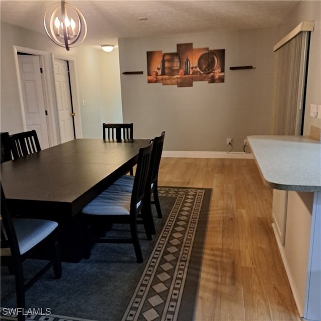 dining area with baseboards, a notable chandelier, and wood finished floors