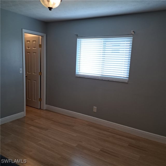 spare room with baseboards and wood finished floors
