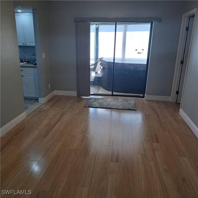 unfurnished dining area featuring baseboards and wood finished floors