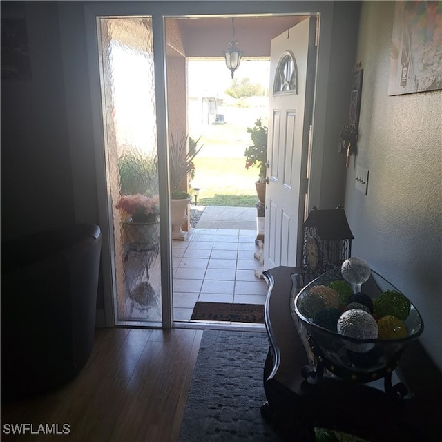 doorway to outside with a textured wall and wood finished floors