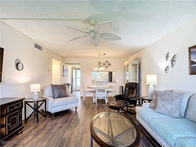 living room with dark hardwood / wood-style flooring, ceiling fan with notable chandelier, and a textured ceiling