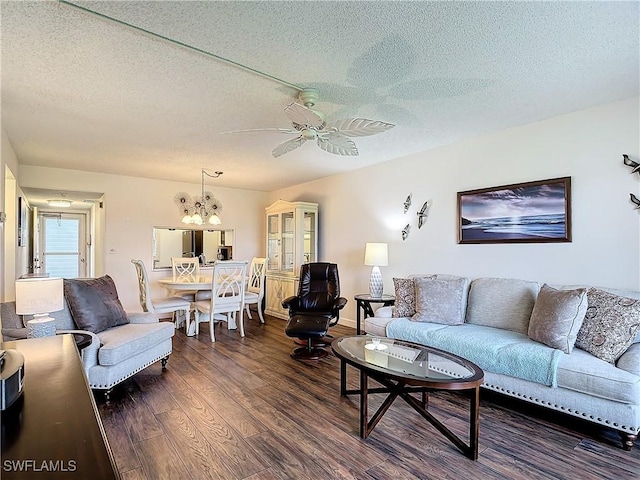 living room featuring dark hardwood / wood-style flooring, ceiling fan with notable chandelier, and a textured ceiling